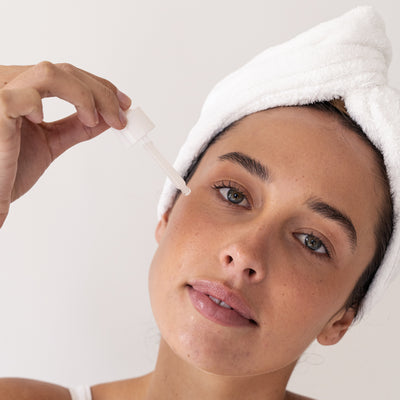 young female using About time we met's repair serum after showering